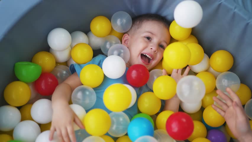 A child play in dry pool with colored balls. happy family kid dream concept. dry pool interactive room in kindergarten. a child play in a children room in a dry lifestyle pool with balls | Shutterstock HD Video #1102673925