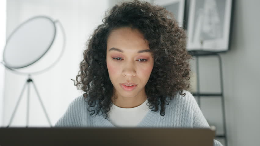 Close up view on uncertain clueless woman with Afro hair hesitates about something, feels puzzled dressed in casual blue sweater, modern apartment background. Indecisive questioned young female indoor Royalty-Free Stock Footage #1102675473