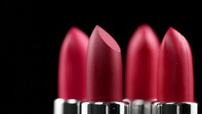 Lipstick. Fashion red Colorful Lipsticks isolated on black background, close up. Red lipstick tints palette, Professional Makeup and beauty. Beautiful Make-up concept. Lipgloss. Rotating Lipsticks