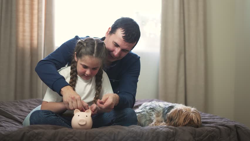 family path to financial security. valuable lessons in budgeting.dad teaches his child to save money.Father and daughter make investments using piggy bank.Saving family money.Father and child teamwork Royalty-Free Stock Footage #1102684329