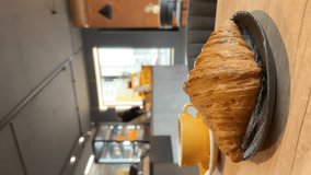 Close-up of hands tearing a fresh croissant into halves, at the wooden table in a bakery. People in bokeh, atmosphere of a coffee shop. Lifestyle vertical video. - Powered by Shutterstock - Get 15% off with code: PIKWIZARD15
