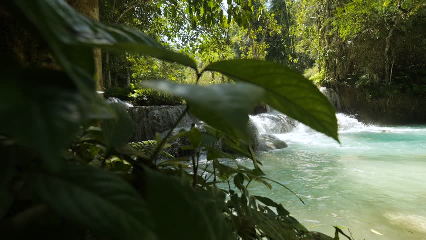 Kuang Si Waterfall - Popular Touristic Destination, Luang Prabang, Laos. Beautiful Clear Water Waterfall Cascade in Tropical Rainforest Jungle Wide Angle Lens Natural Wildlife 4K Slowmotion Footage. Royalty-Free Stock Footage #1102698209