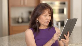 Close up stylish beautiful woman wearing purple sleeveless reading scrolling mobile table email communications sitting in home kitchen. Attractive mature female using cellular business technology - Powered by Shutterstock - Get 15% off with code: PIKWIZARD15