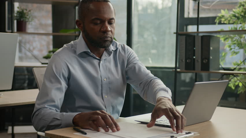 Tired mature worker African American man work with documents laptop suffer migraine ache exhausted businessman feel eye strain after paperwork eyestrain tension massaging dry eyes overwork in office Royalty-Free Stock Footage #1102704771