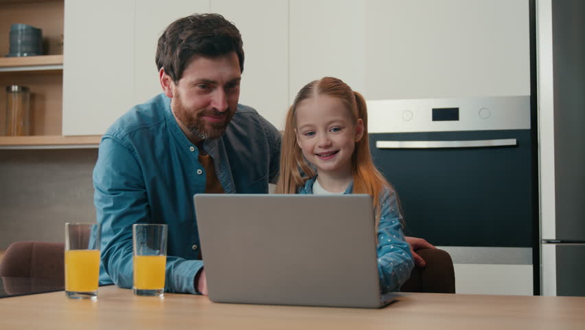 Parental control Caucasian father teaching little daughter using laptop app at home kitchen dad explain computer software help with e-learning online browsing child kid girl happy family with juice Royalty-Free Stock Footage #1102704785