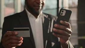 Close up credit bank card unknown African American adult man businessman banker in office pay online on mobile phone money finances paying shopping ecommerce enter secure code safe transaction payment - Powered by Shutterstock - Get 15% off with code: PIKWIZARD15