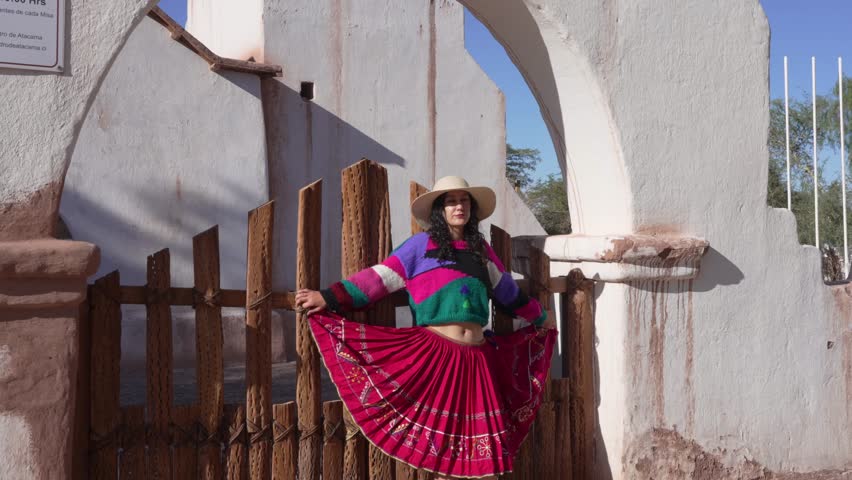 portrait of latin woman dressed in inspired Andean traditional clothes with background of an old church in san pedro de atacama