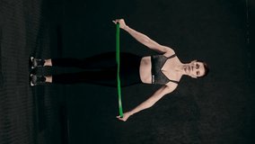 Adult athletic woman exercising in the gym, female athlete using rubber elastic resistance tubes in her daily workout Real people, health and fitness, concept, vertical video
