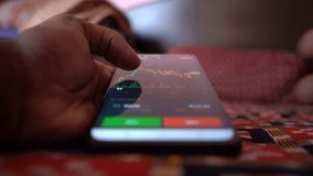 Closeup of person checking stock market chart and candlestick pattern on mobile phone 