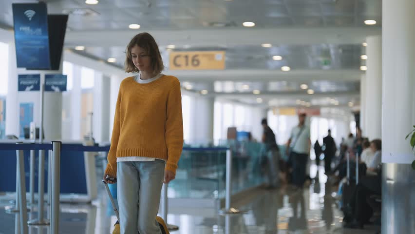 Tween girl with suitcase walking in airport terminal. Royalty-Free Stock Footage #1102715999