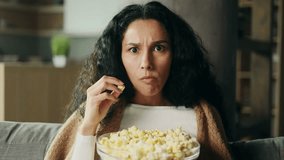 Camera view of addicted focused young hispanic woman watching interesting TV program film movie and eating popcorn alone at home Enchanted curly girl cannot take her eyes off the screen indoors - Powered by Shutterstock - Get 15% off with code: PIKWIZARD15