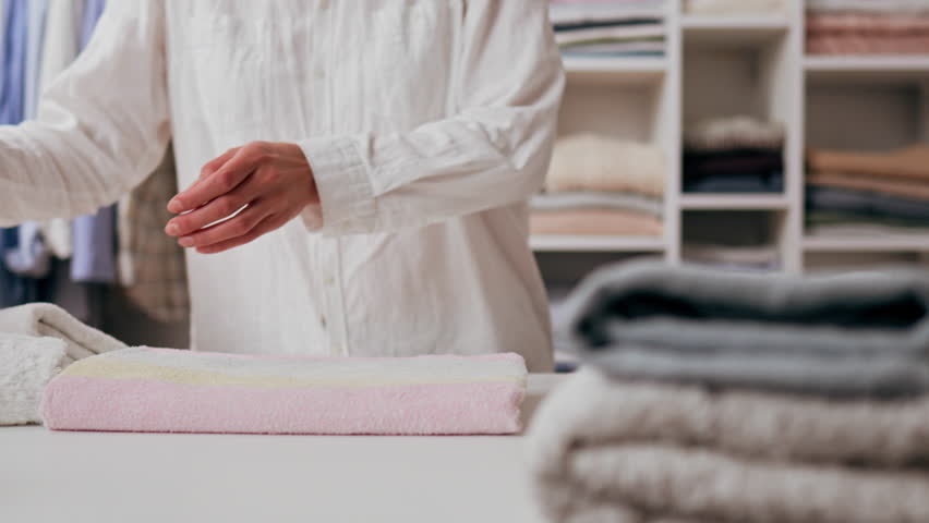 Young housewife mom folds a stack of towels fresh washed linen is stacked in a wardrobe closet. House cleaning. A young mother puts things in order in the wardrobe closet for clothes
 Royalty-Free Stock Footage #1102719459