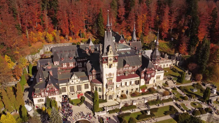 Aerial around view of Peles Castle in autumn forest, Sinaia, Romania. Summer residence of the kings of Romania, 4k