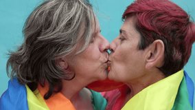 Happy gay senior lesbian couple kissing wearing lgbt rainbow flag outdoors - Diversity family love - Powered by Shutterstock - Get 15% off with code: PIKWIZARD15