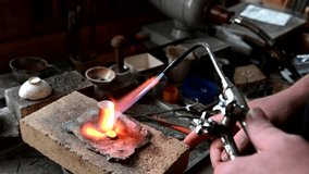 Gold wedding ring making by goldsmith, isolated, Jeweler melts gold in liquid state in crucible. Macro video. Craft jewelry making with professional tools. Process of making handmade. Metal melting