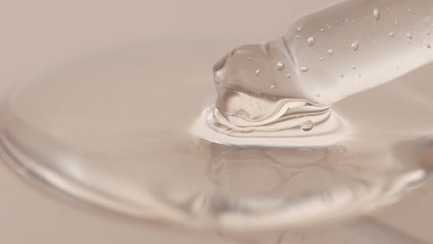 Cosmetic pipette with beauty gel close-up on a beige background, front view. Skin moisturizer, anti-aging.