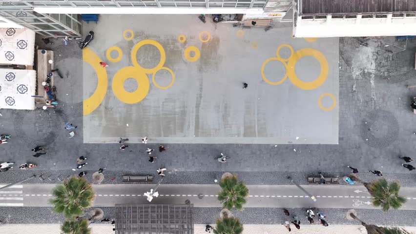 Gordon beach boardwalk , Tel Aviv Israel .people walking around ,riding scooters and bicycles  . top down aerial view.
