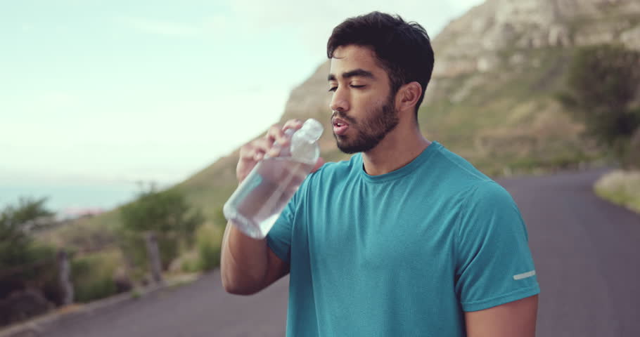 Drinking water, fitness and tired man outdoor training, exercise or workout nutrition, health and wellness. Liquid bottle on diet, sports goals and cardio runner, athlete or indian person on mountain Royalty-Free Stock Footage #1102734337