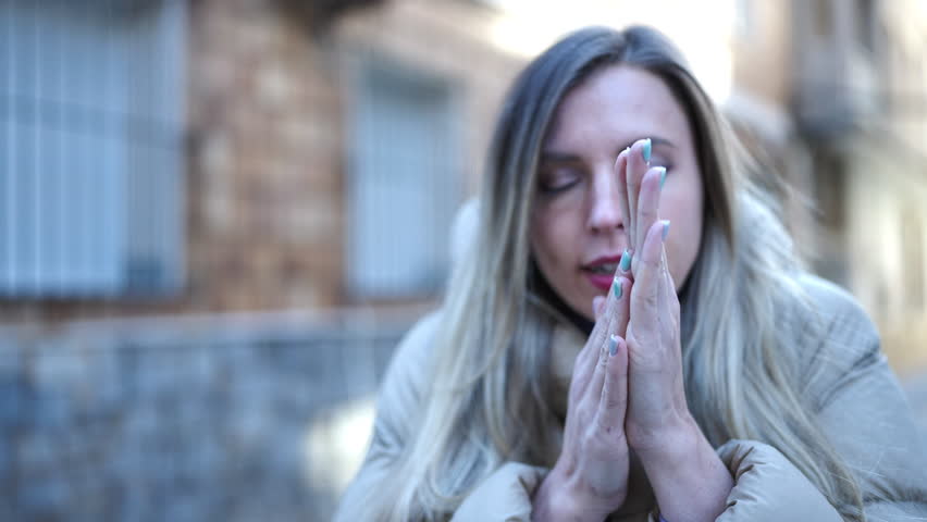 Young blonde woman rubbing hands for cold at street