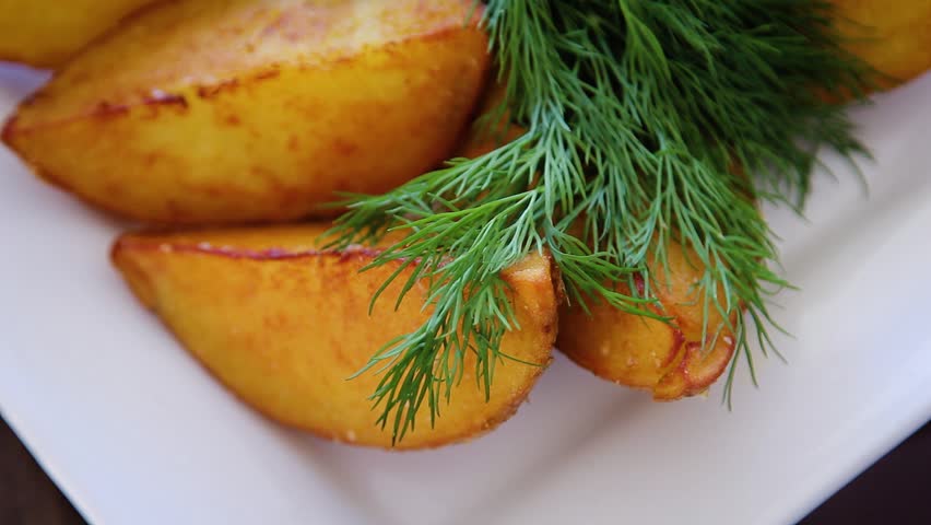 Close-up baked potato with green parsley on a white plate, smooth camera movement, selective focus.