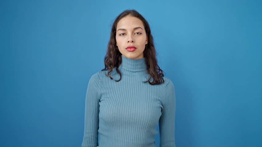 Young beautiful hispanic woman smiling confident holding money over isolated blue background