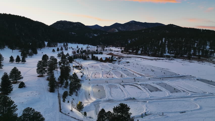 Mid winter Colorado Evergreen Lake under lights sunset playing hockey and ice skating at various rinks pan left