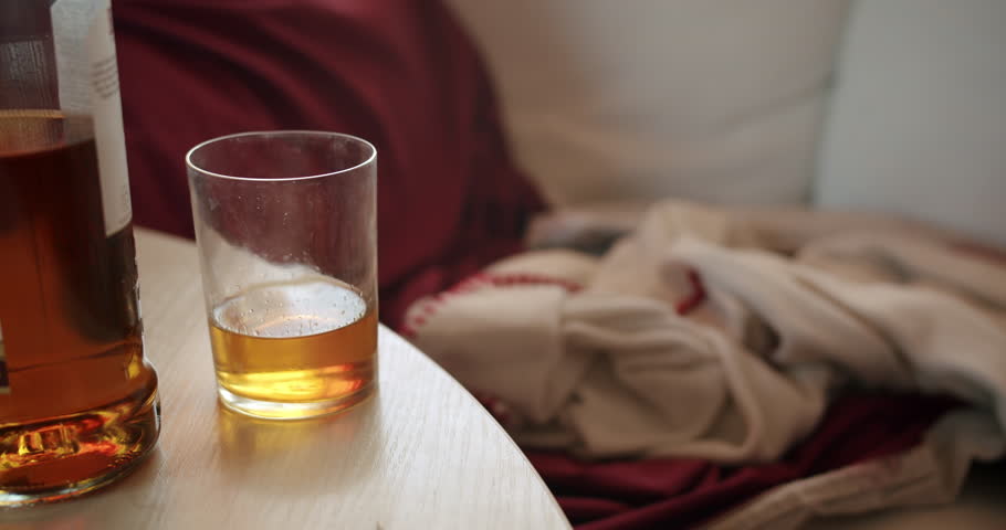 Alcoholic man with an alcohol addiction problem drinking daytime. Falling on the couch to have just another wiskey, next drink dose. Want to kill hangover. Binge drinking. Whiskey glass and bottle Royalty-Free Stock Footage #1102748555