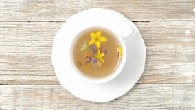 Healthy herbal tea in a white cup with medicinal herbs and flowers for relaxation and wellness. Floral Infusion,  top view, vertical video