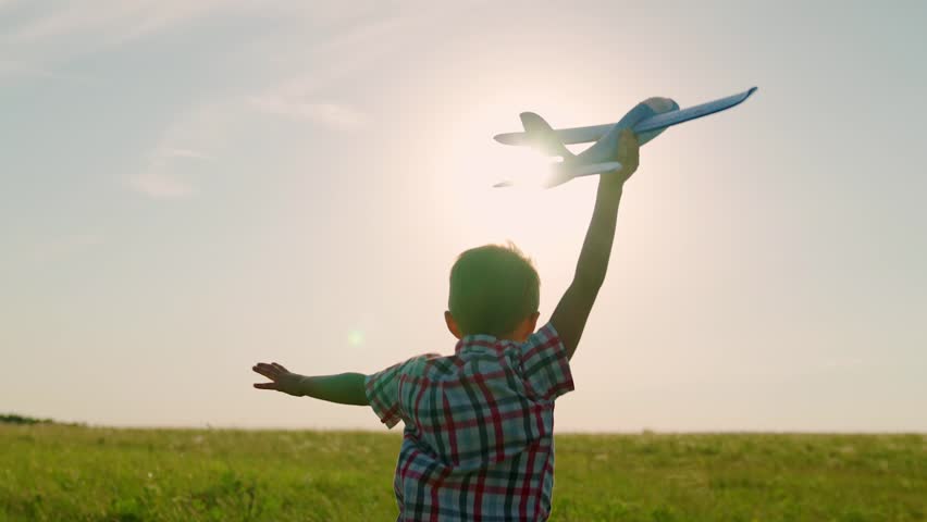 Boy child flies into his future. Child boy runs with toy airplane on field, sun. Boy wants to become pilot astronaut. Slow motion. Child play toy airplane. Teenager dreams of flying, becoming pilot