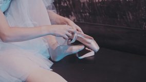 A ballerina puts pointe shoes on her feet while sitting on stage backstage before a performance. Professional ballet. The artist behind the scenes. - Powered by Shutterstock - Get 15% off with code: PIKWIZARD15