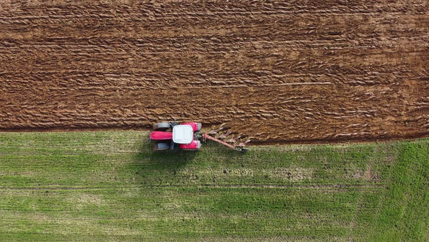 Tractor ploughing a meadow of green grass. View from above with a drone. Royalty-Free Stock Footage #1102750933