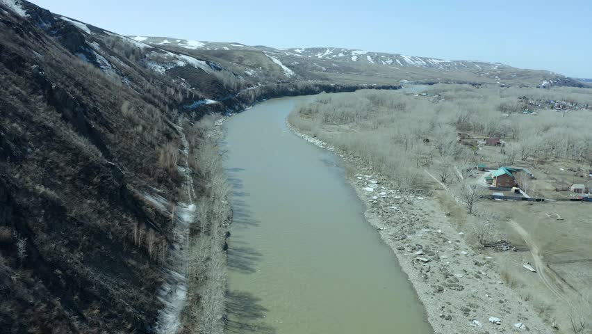 Aerial - Flying low above the turquoise color river carving its way through the spring valley