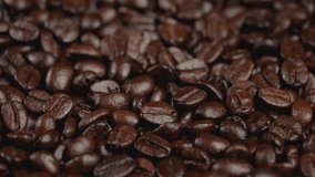 Dark coffee beans are rotating. Close-up of organic coffee seeds. Slow motion video.