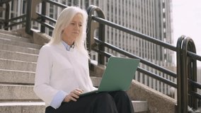 Businesswoman greeting the laptop during an online meeting outdoors