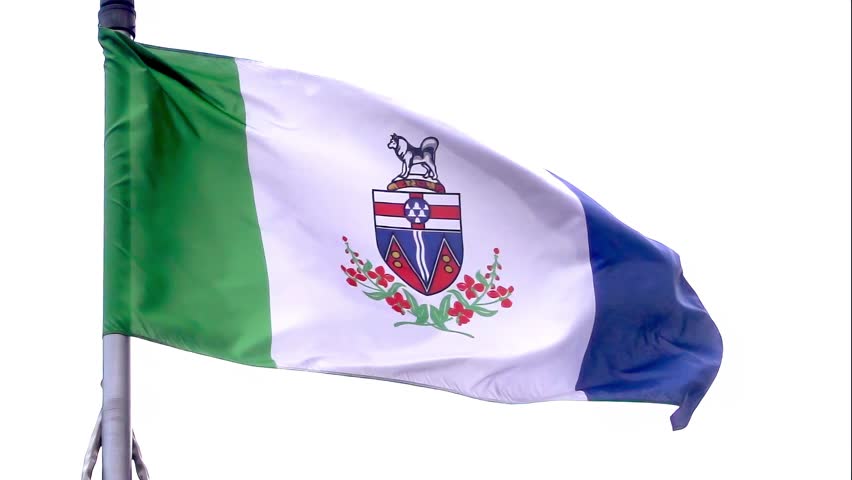 A waving flag of Yukon, a green, white, and blue tricolour with the coat of arms of Yukon at the centre above a wreath of fireweed, the territorial flower.