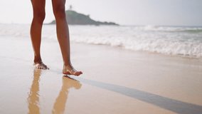 Black woman feet walking on sandy ocean beach at exotic island along sea water waves. Dark skin female legs go by surf line, touch white foam. Bipoc girl relaxing on tropical travel at luxury resort. - Powered by Shutterstock - Get 15% off with code: PIKWIZARD15