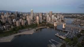 Aerial footage of West End area and Second Beach in Downtown Vancouver, BC Canada with view of Burrard and Granville bridges during the dusk hour with view of shimmering lights from buildings