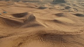 Cars drive off-road on the sand dunes of the desert, drone video