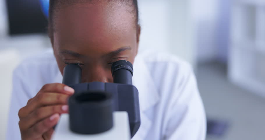 Black woman, scientist with microscope and analysis of DNA for science study with scientific innovation. Doctor analyze particles, female focus while doing medical research in laboratory and biotech Royalty-Free Stock Footage #1102770487