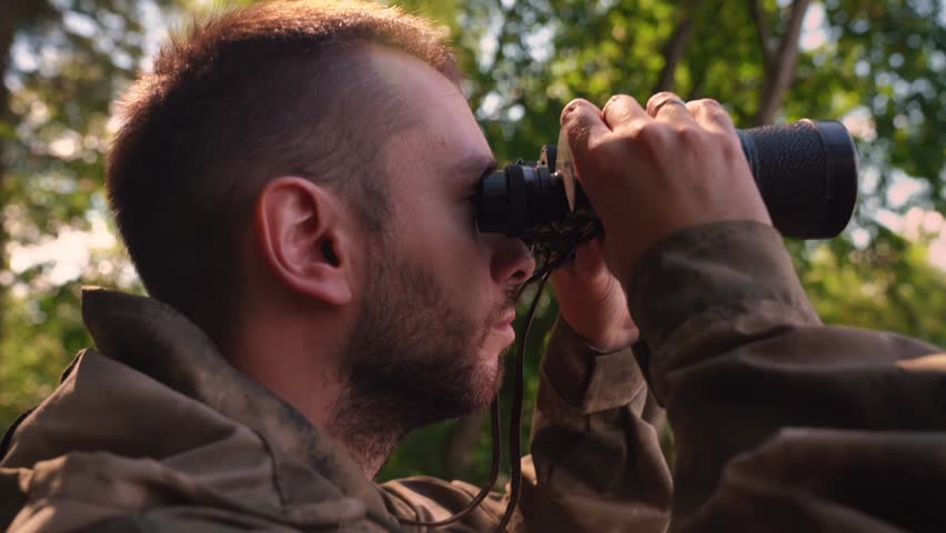 Ranger or hunter with binocular observing forest. young soldier walking through Forest near lake. Portrait close up Royalty-Free Stock Footage #1102771235