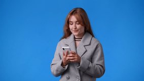 4k video of one girl is so excited about something and using the phone over blue background.