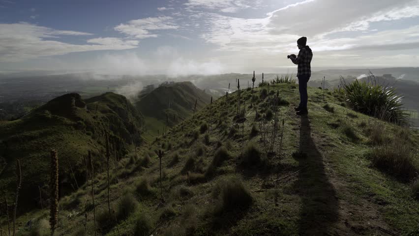 Man taking photos with a camera on the peak of a mountain on a foggy morning. 4k video