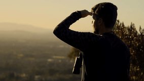 Man standing on a lookout at the top of mountain and watching through binoculars. horizontal video