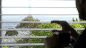 Young man drinking coffee and watching through window at beautiful landscape. Horizontal 4k video