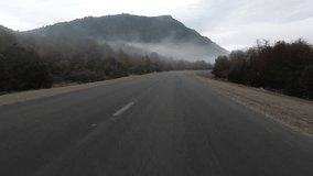 Traveling. Point of view of a car driving along the rural road across the trees and mountains, early in the morning. View of the fog and mist in the environment. - Powered by Shutterstock - Get 15% off with code: PIKWIZARD15