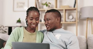 Laptop, movie and black couple laugh on a living room sofa with love and happiness. Web series, laughing and happy woman with man together on a lounge couch online streaming a video in a house