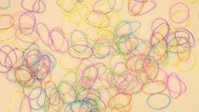 Hands taking bunch of colorful rubber bands and through them al over on yellow background. Bright office rubber bands. Multicolored elastic rubber bands close up.