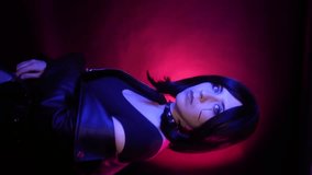 Vertical video shot on a smartphone, young woman with a bob hairstyle in a black leather jacket, with a spiked collar, posing on a dark background with blue and red highlights, cyberpunk concept. - Powered by Shutterstock - Get 15% off with code: PIKWIZARD15