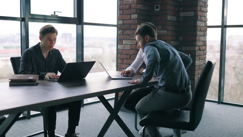Three colleagues working together on a laptop, receiving guidance from their mentor. A team of young professionals working diligently on their laptops in a modern office environment. Royalty-Free Stock Footage #1102783843