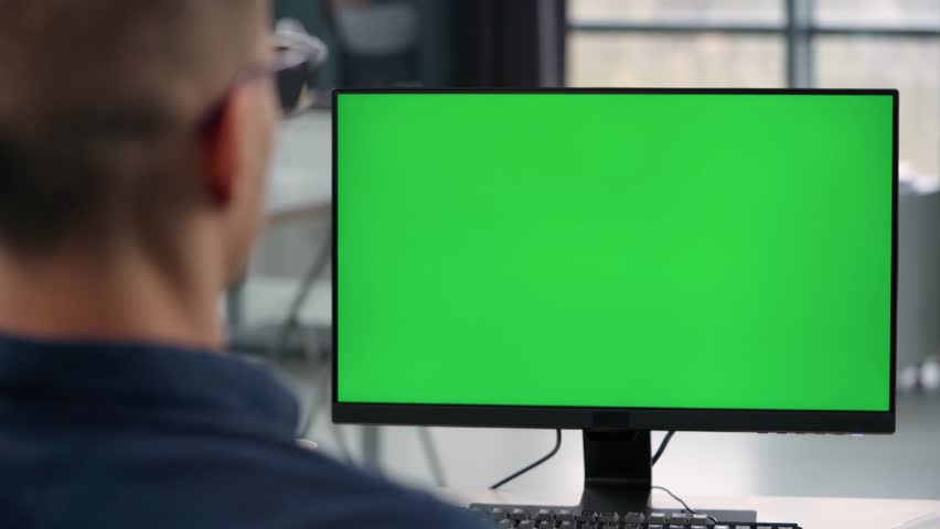 Young Man Working At Computer With Green Mock Up Screen in Office. Close Up Desktop Computer Monitor with Mock Up Green Screen Chroma Key Display Royalty-Free Stock Footage #1102785499